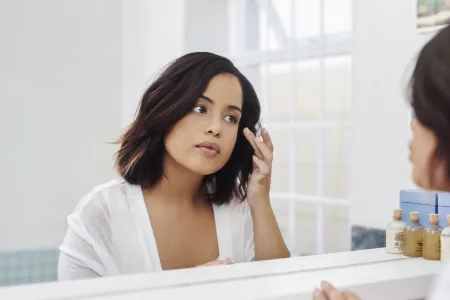 Woman checking her skin in the mirror