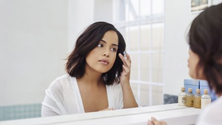 Woman checking her skin in the mirror